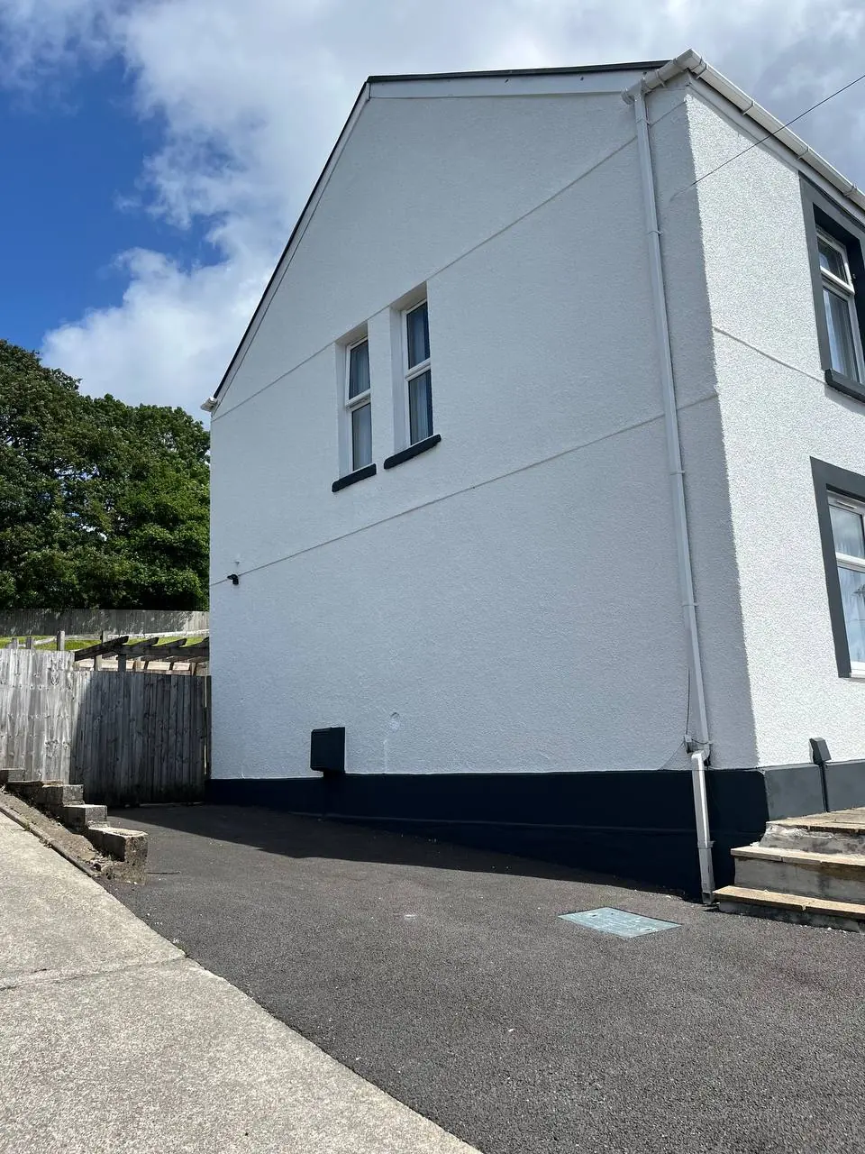 After: the same gable end in clean brilliant white with a black painted plinth and black rainwater goods.