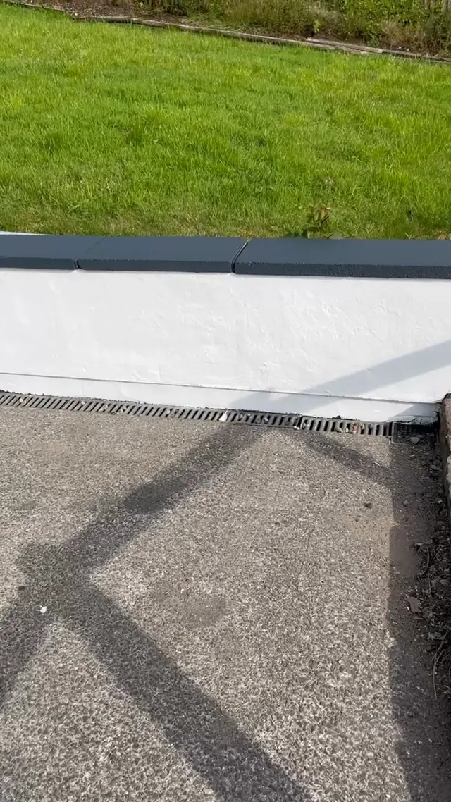 The finished garden retaining wall, painted white with a dark capping.