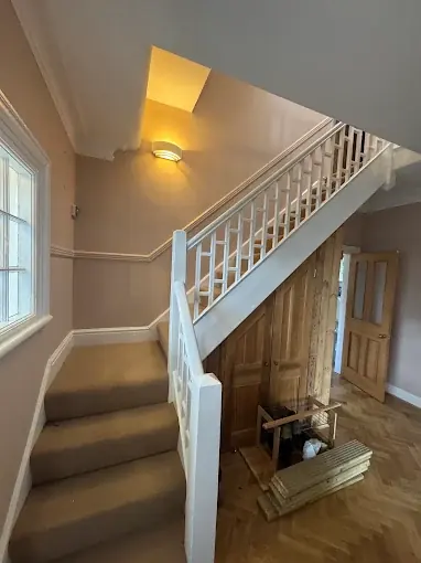 A repainted hallway and staircase in a Swansea home, with freshly finished spindles and doors.