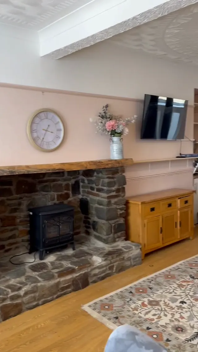A finished Swansea living room in soft blush with white picture rail, coving and a stone fireplace.