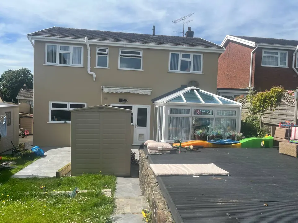 After: the same rear elevation recoated in a warm stone colour, with the shed painted to match.