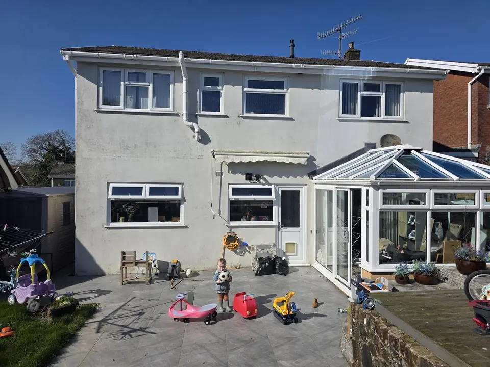 Before: the rear of a Swansea family home in weathered white render.